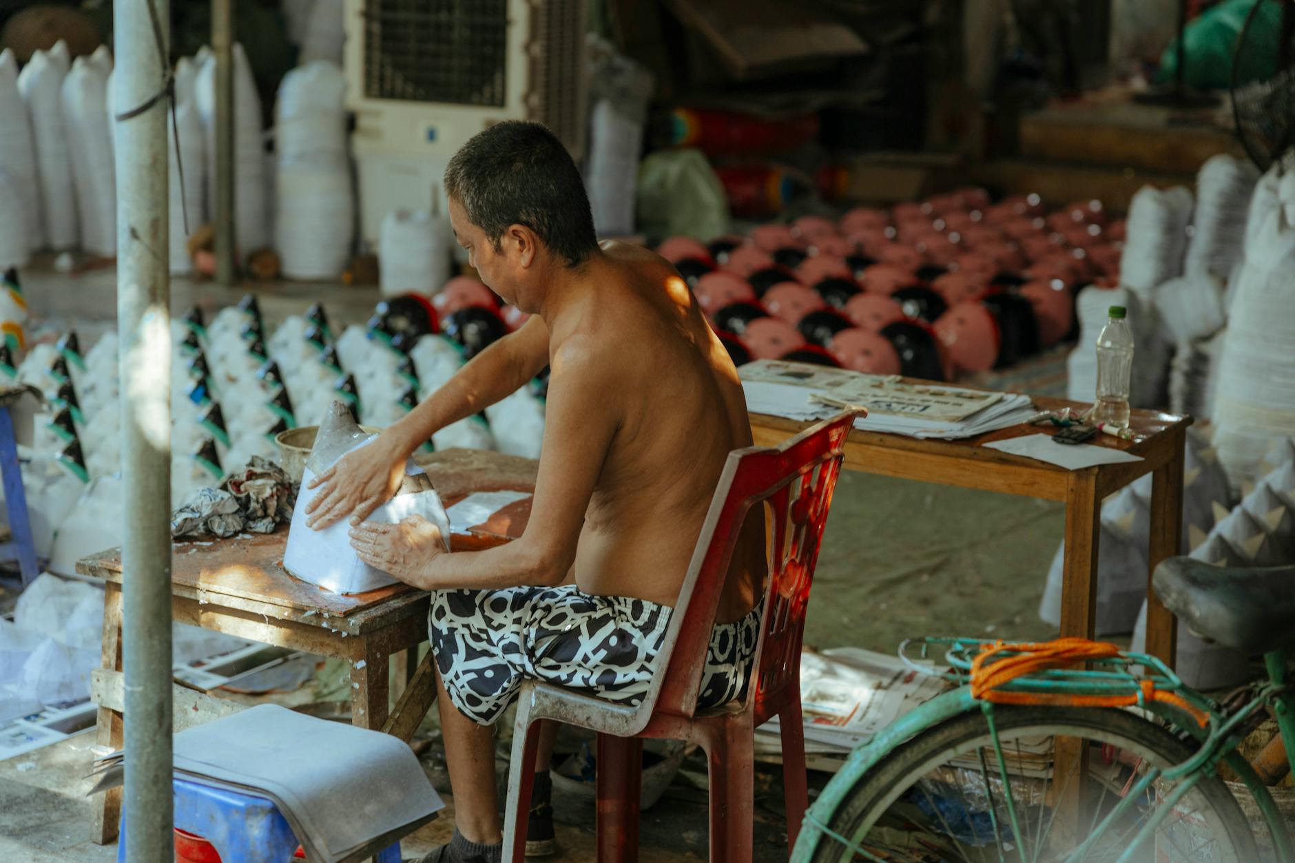 ช่างฝีมือกำลังวาดลวดลายบนร่มกระดาษที่บูธสาธิตภายในเทศกาล