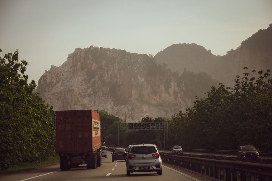 Cars travelling on a Malaysian expressway beside limestone hills. Photo by shun idota on Unsplash
